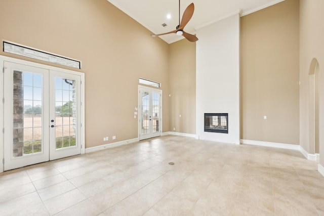 unfurnished living room with french doors, a towering ceiling, ceiling fan, and light tile patterned floors