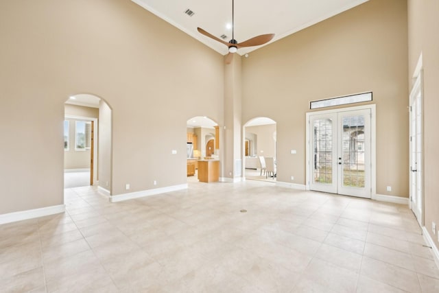 unfurnished living room with light tile patterned flooring, ceiling fan, french doors, and a wealth of natural light