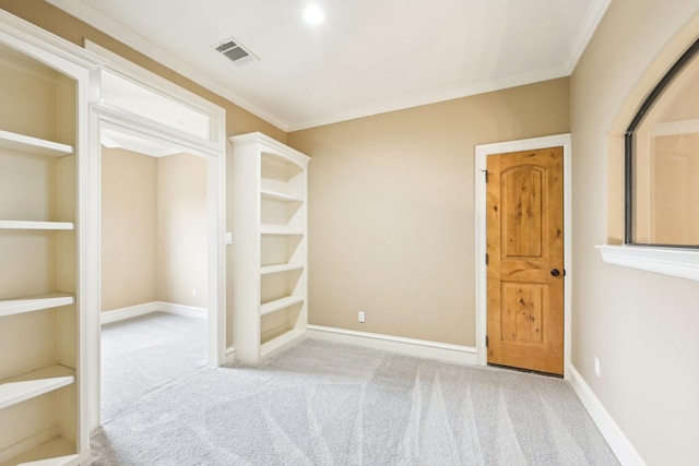 unfurnished room featuring crown molding, light colored carpet, and built in shelves