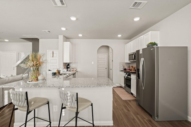 kitchen featuring sink, kitchen peninsula, light stone countertops, white cabinetry, and stainless steel appliances