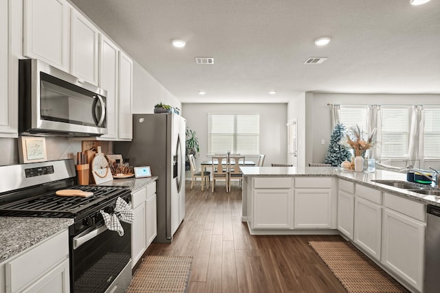 kitchen featuring light stone countertops, stainless steel appliances, sink, dark hardwood / wood-style floors, and white cabinetry