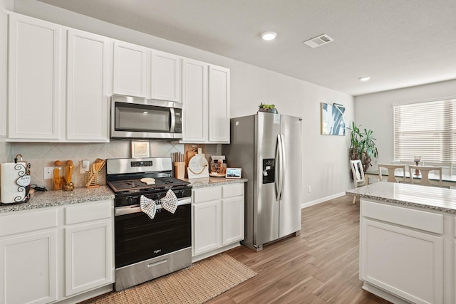 kitchen featuring light stone countertops, white cabinets, and stainless steel appliances