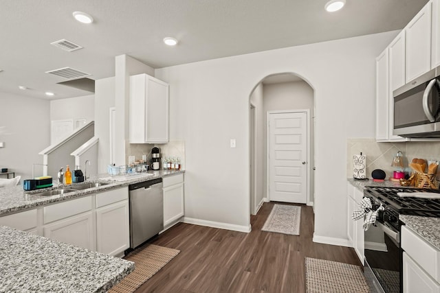 kitchen with light stone counters, stainless steel appliances, sink, dark hardwood / wood-style floors, and white cabinetry