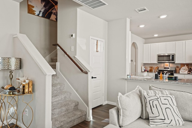 kitchen featuring light stone countertops, stainless steel appliances, white cabinetry, and dark hardwood / wood-style floors