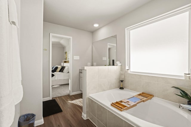 bathroom with hardwood / wood-style floors, vanity, and tiled bath