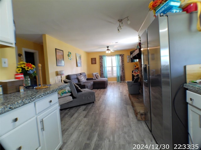 kitchen with ceiling fan, stainless steel fridge, light stone countertops, light wood-type flooring, and white cabinetry