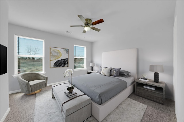 bedroom with ceiling fan, light colored carpet, and multiple windows