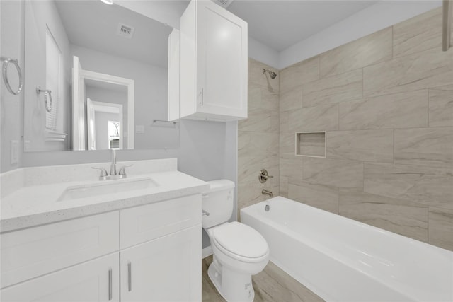 full bathroom with vanity, tiled shower / bath, and toilet