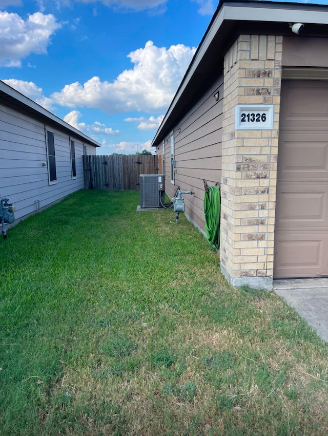 view of yard with central AC and a garage