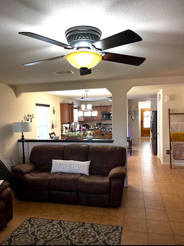 living room with ceiling fan, light tile patterned floors, and a textured ceiling