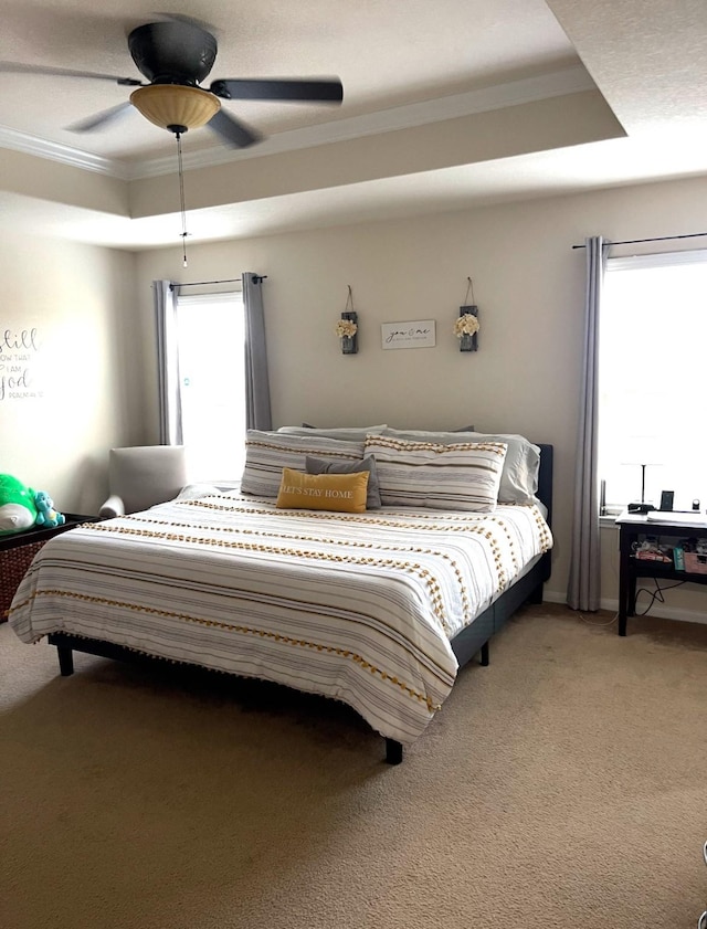 bedroom featuring a raised ceiling, ceiling fan, crown molding, and carpet