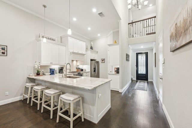 kitchen with pendant lighting, kitchen peninsula, sink, stainless steel fridge with ice dispenser, and white cabinets