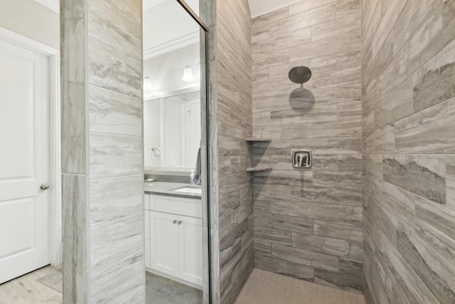 bathroom with vanity, tiled shower, and ornamental molding