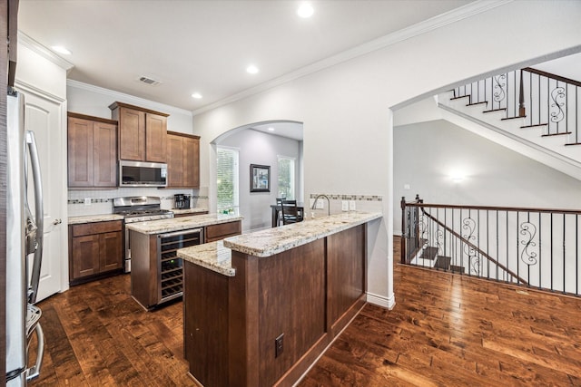 kitchen with wine cooler, light stone countertops, dark wood-type flooring, and appliances with stainless steel finishes