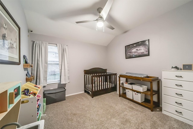 carpeted bedroom with ceiling fan, vaulted ceiling, and a nursery area