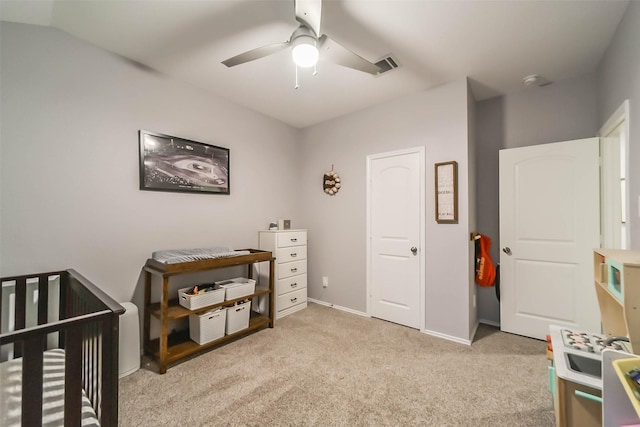 bedroom with ceiling fan, light colored carpet, and a crib