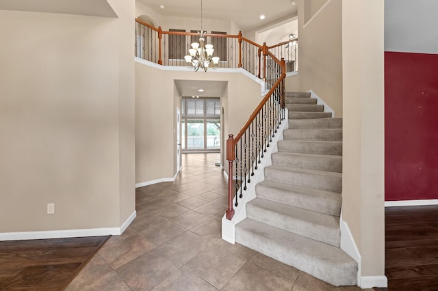 stairs with tile patterned floors, a towering ceiling, and a notable chandelier