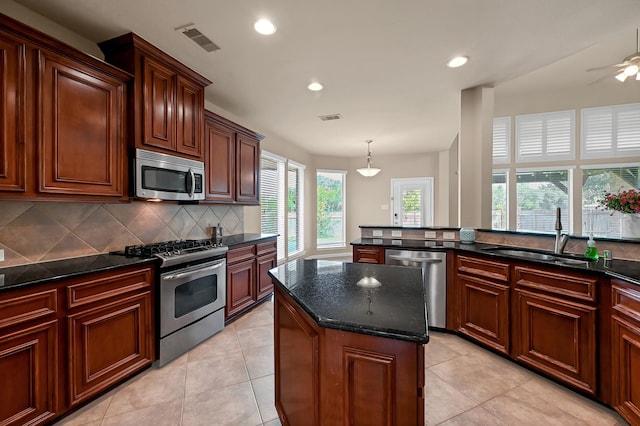 kitchen featuring appliances with stainless steel finishes, backsplash, a wealth of natural light, sink, and a center island