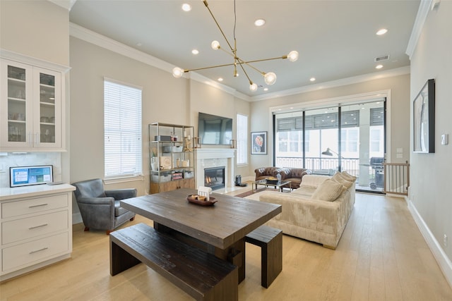 living room with crown molding, an inviting chandelier, and light hardwood / wood-style floors