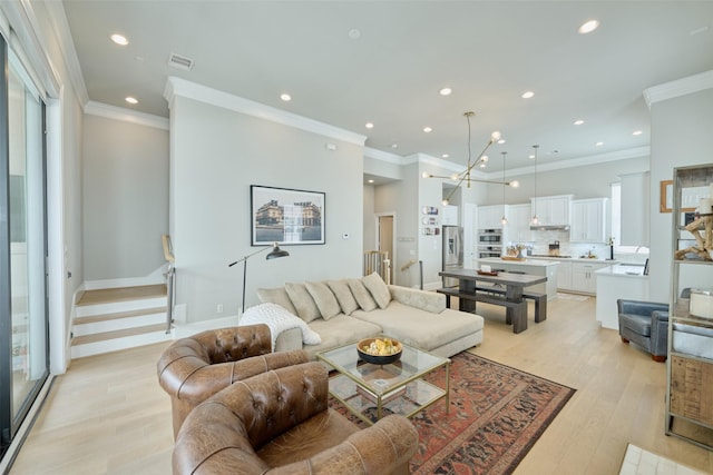 living room with crown molding, a chandelier, and light hardwood / wood-style floors