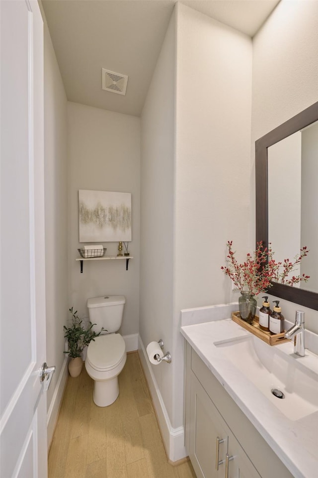 bathroom with vanity, toilet, and wood-type flooring