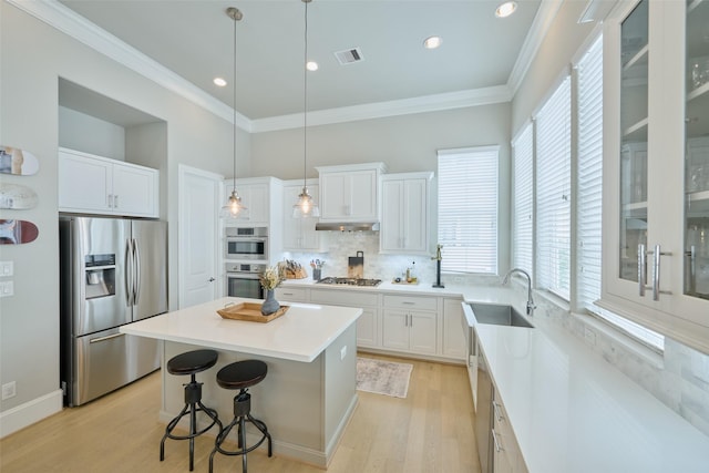 kitchen with sink, a center island, appliances with stainless steel finishes, pendant lighting, and white cabinets