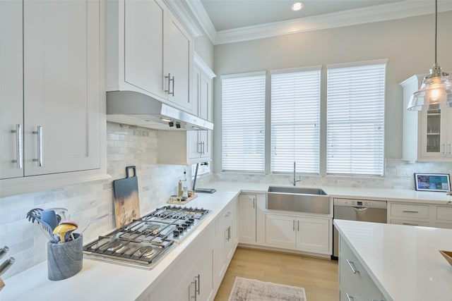 kitchen featuring appliances with stainless steel finishes, sink, white cabinets, hanging light fixtures, and ornamental molding