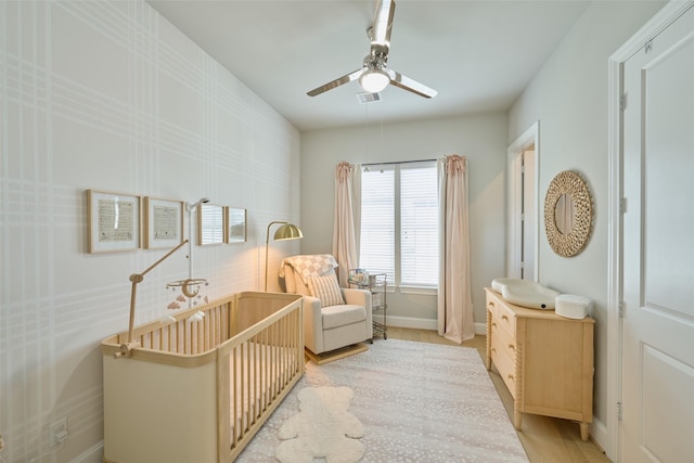 bedroom featuring a nursery area and ceiling fan