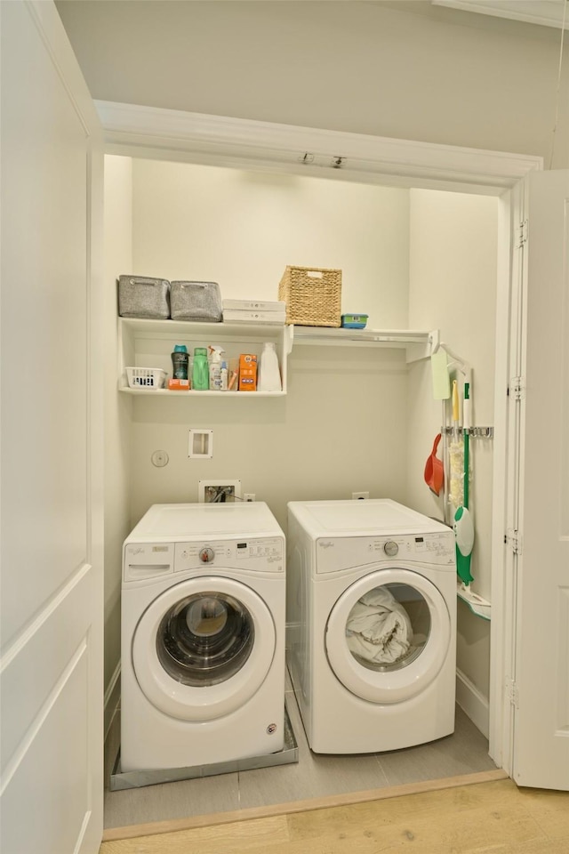 clothes washing area with washing machine and dryer and light wood-type flooring