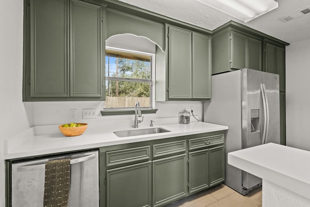 kitchen with dishwasher, light tile patterned floors, green cabinets, and sink