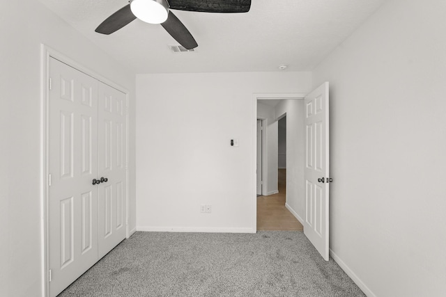 unfurnished bedroom featuring ceiling fan, a closet, and light colored carpet