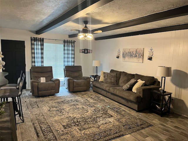 living room featuring ceiling fan, a textured ceiling, beamed ceiling, and wood finished floors