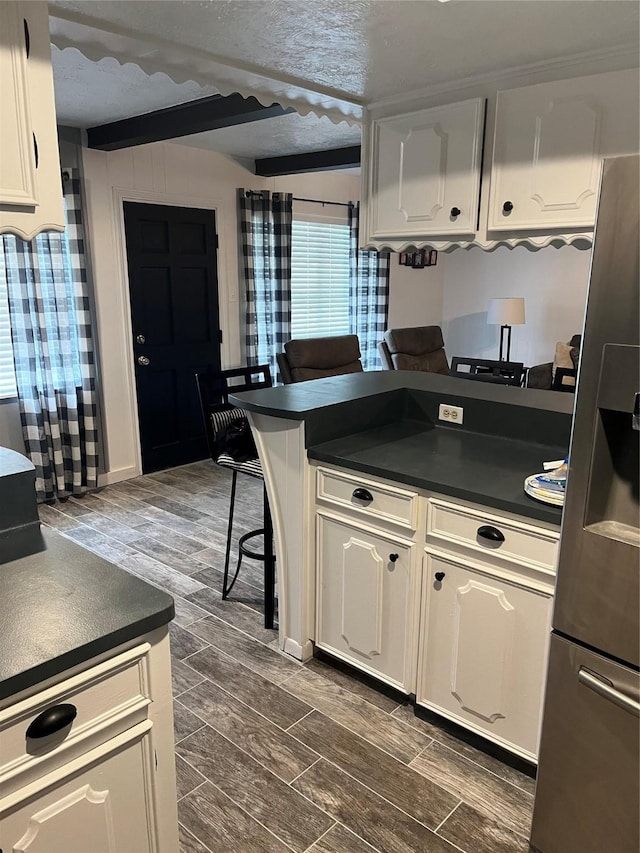 kitchen featuring dark countertops, wood finish floors, and stainless steel fridge