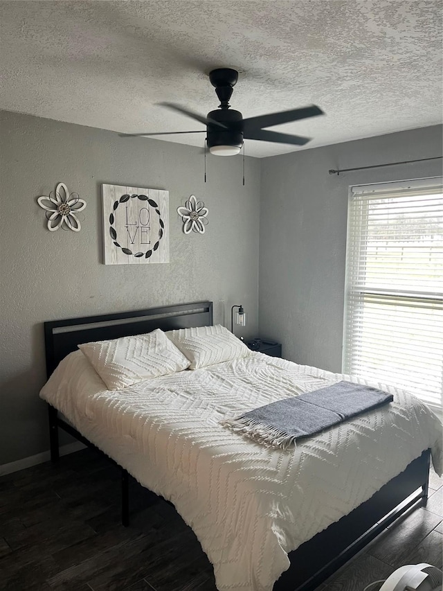 bedroom with a textured ceiling, a textured wall, ceiling fan, wood finished floors, and baseboards