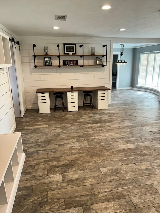 unfurnished office with dark wood-style floors, a barn door, visible vents, and recessed lighting