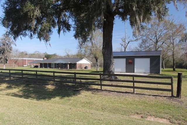 view of yard featuring a garage, fence, and an outbuilding