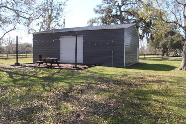 view of outdoor structure with fence and an outbuilding