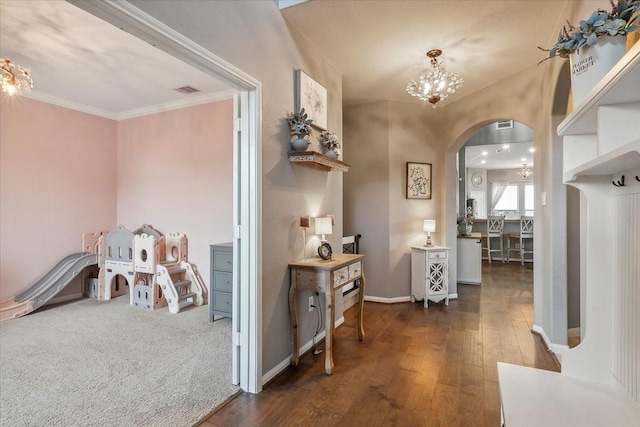 hall featuring dark hardwood / wood-style floors, crown molding, and an inviting chandelier