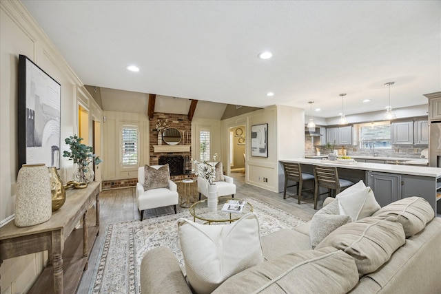 living room featuring sink, a fireplace, light hardwood / wood-style floors, and plenty of natural light