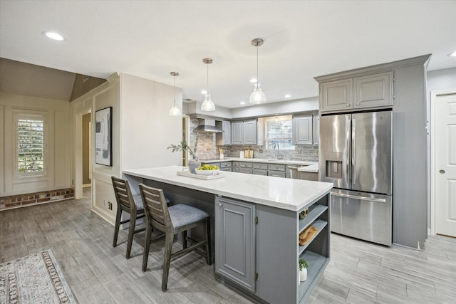 kitchen with kitchen peninsula, decorative backsplash, hanging light fixtures, gray cabinetry, and appliances with stainless steel finishes