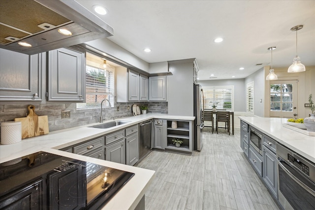 kitchen with sink, stainless steel appliances, island range hood, pendant lighting, and gray cabinetry