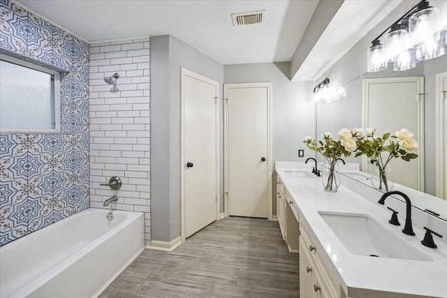 bathroom with tiled shower / bath combo and vanity