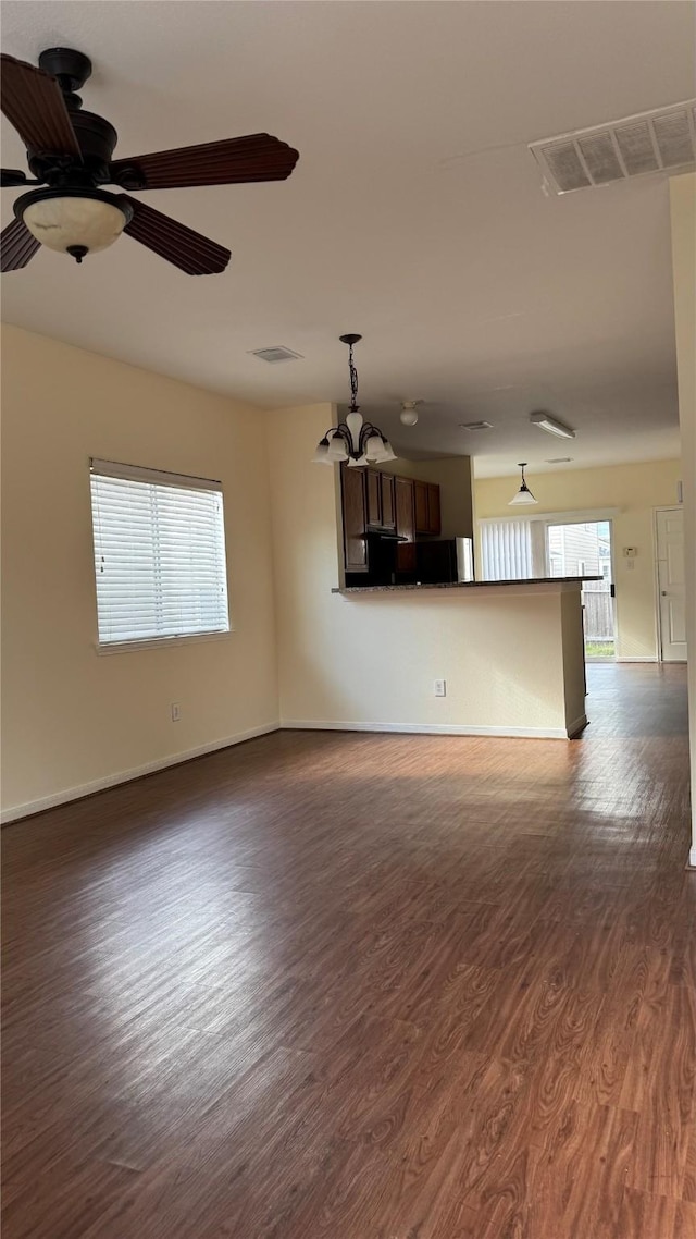 unfurnished living room with dark hardwood / wood-style flooring and ceiling fan with notable chandelier