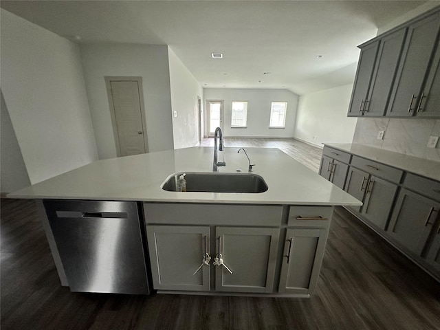 kitchen featuring gray cabinetry, dishwasher, a center island with sink, sink, and decorative backsplash