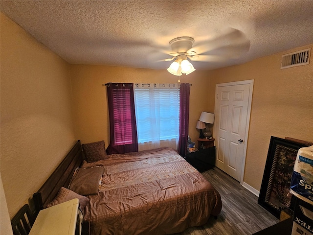 bedroom featuring ceiling fan, dark hardwood / wood-style floors, and a textured ceiling