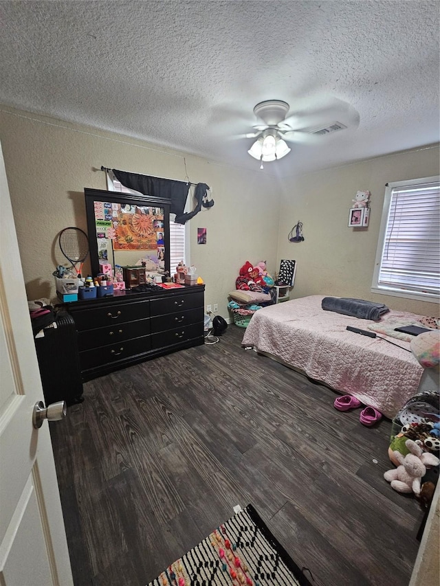 bedroom featuring ceiling fan, dark hardwood / wood-style flooring, a textured ceiling, and multiple windows