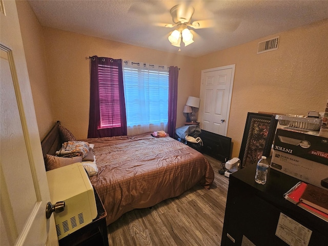 bedroom with ceiling fan, wood-type flooring, and a textured ceiling