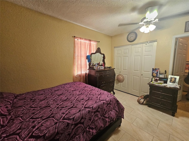 bedroom featuring ceiling fan, light tile patterned floors, and a textured ceiling