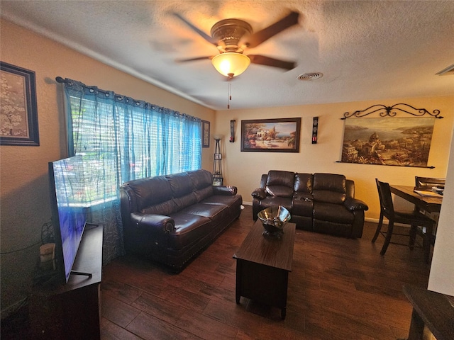 living room with ceiling fan, dark wood-type flooring, and a textured ceiling