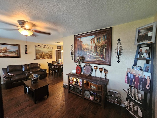 living room featuring ceiling fan, dark hardwood / wood-style flooring, and a textured ceiling